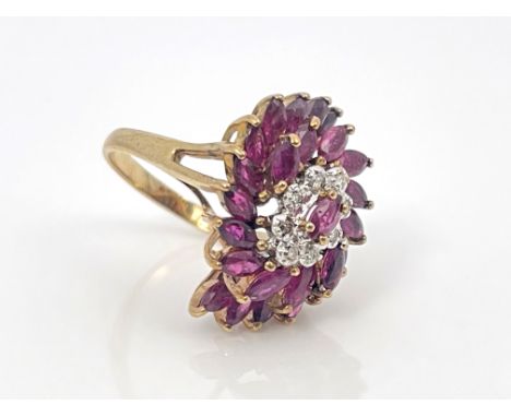 A 9 carat gold ruby and diamond dress ring, the central diamond cluster within a double spiral of rubies, 5.9g