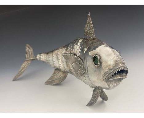 A Continental silver sculpture modelled as a fish, articulated body with simulated scales and fins, head with green glass eye