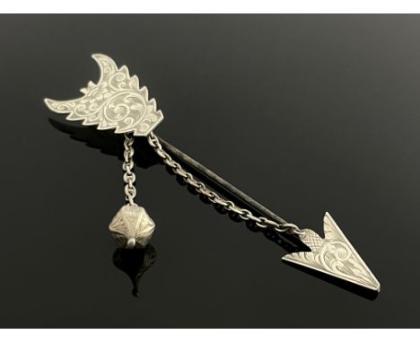 A Victorian white metal cape pin, in the form of an arrow, with chased foliate scroll flight and arrowhead, the safety chain 