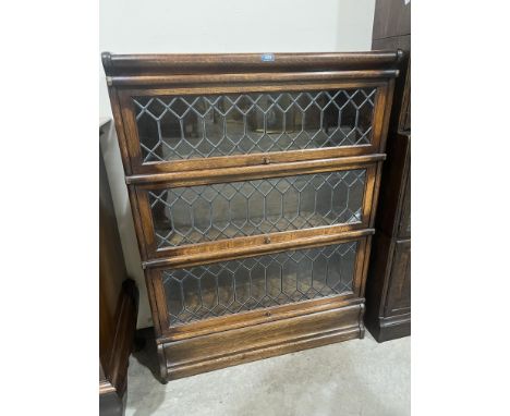 An oak Globe-Wernicke bookcase in three sections, each enclosed by a diamond pane leaded light door. 45' high (Two small pane