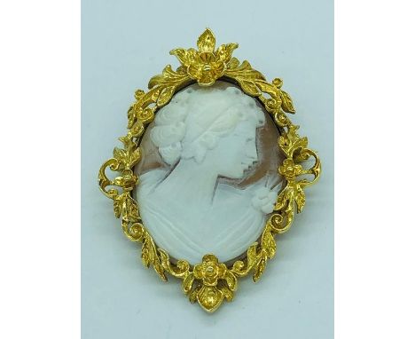 A Cameo of a lady in classical style set in a yellow metal foliate design surround.