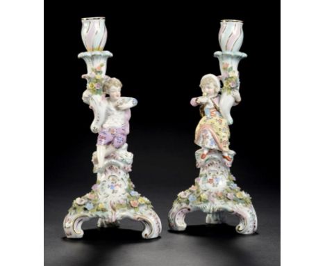 A PAIR OF SITZENDORF FIGURAL AND FLORAL ENCRUSTED CANDLESTICKS, C1900  on three scroll feet, 27cm h, crossed lines ++Typical 