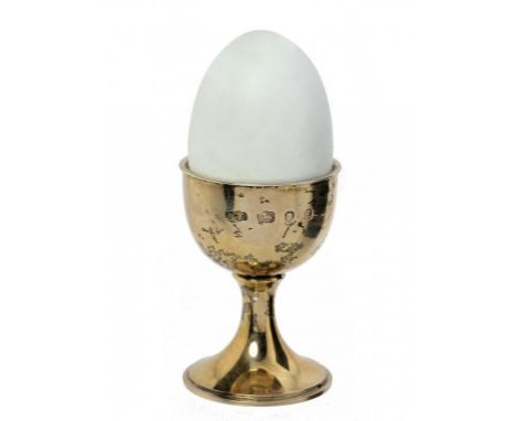 AN ELIZABETH II SILVER GILT AND EGGSHELL ENAMEL EGG AND EGG CUP BY ANTHONY ELSON   containing a basket of egss 'surprise', 10