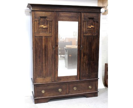 A large 1930s oak panel wardrobe with Secessionist-style checkered inlay to the panels flanking the bevel glass mirrored door