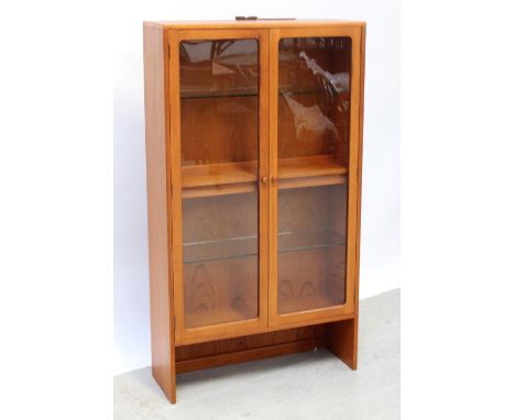 A G-Plan style twin-door glazed cabinet with one interior shelf, on slab-end supports, 144 x 81cm.