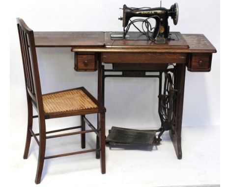 A vintage Singer sewing machine on oak and cast iron treadle base, width approx 88cm and a cane-seated chair (2).