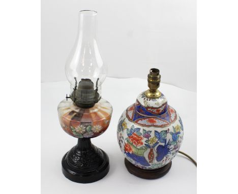 An early-to-mid 20th century oil lamp with floral painted reserve, height 44cm and an Oriental ginger jar on hardwood stand, 