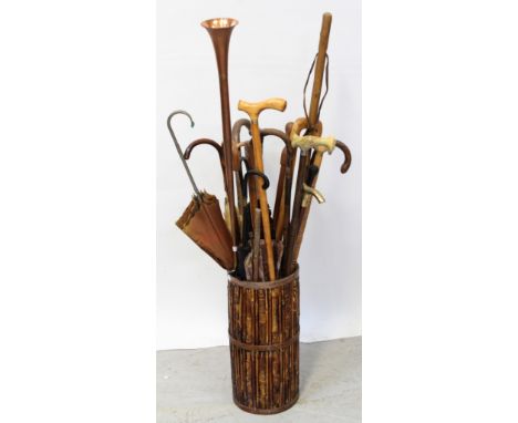 A bamboo stick stand with a selection of vintage umbrellas, walking sticks and a coaching horn, approx length 126cm.