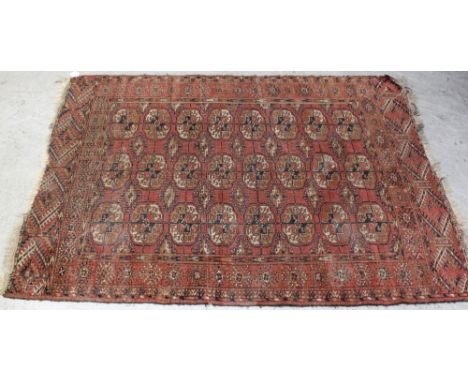 A vintage hand-knotted red ground Bokhara carpet with geometric gul design within a geometric multi-border, 107.5 x 154cm.