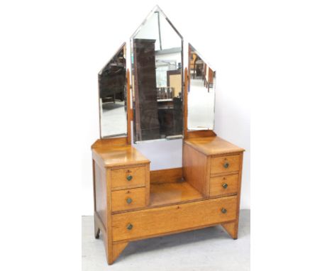 An early 20th century Arts and Crafts triptych dressing table with ecclesiastic triple mirrors over a drop centre base flanke