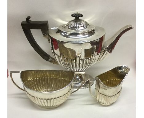 A large silver three piece half fluted tea service on pedestal base. Sheffield. By R&amp;V. Approx. 978 grams. Est. £400 - £6