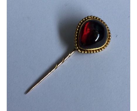 A large cabochon garnet stick pin with ball decoration. Approx. 7 grams. Est. £150 - £200.