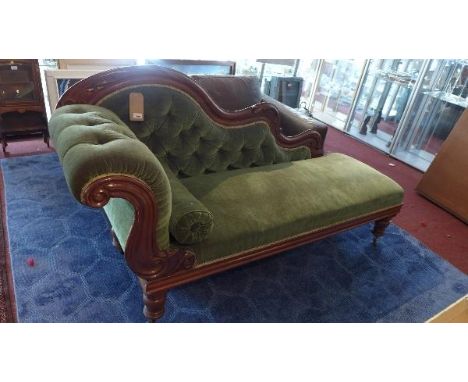 A Victorian mahogany chaise long, with green button back velour upholstery, raised on turned legs and castors 