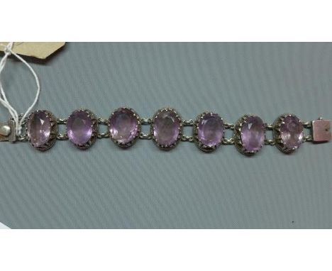 A white metal and amethyst bracelet, the seven oval cut stones set in white metal mounts 