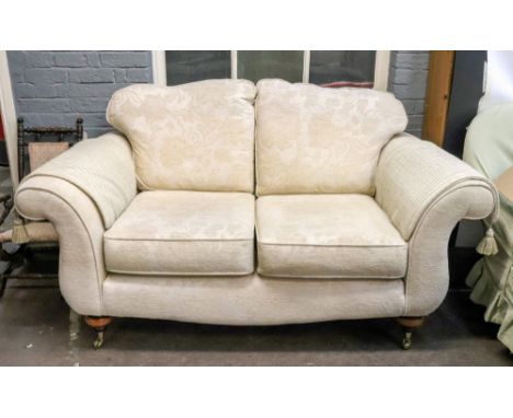 A pair of reproduction two seat settees, with scroll arms, in patterned ivory material, on turned legs and castors, 156cm wid