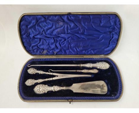 A boxed set of two button hooks, glove stretchers and shoe horn with embossed silver handles