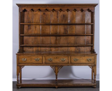 A George III oak dresser, three shelf delft rack, under an ogee moulded cornice, base with three frieze drawers, turned balus