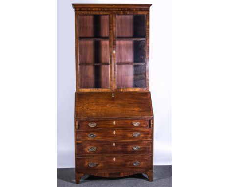 A George III mahogany bureau with a bookcase, cavetto moulded, glazed doors enclosing shelves, the forefront enclosing a fitt