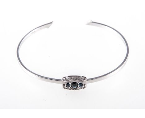 A sapphire and diamond set bangle, three sapphires, oval mixed cut stones, pave set horizontally with a border of eight diamo