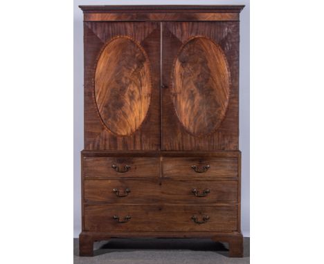 A George III mahogany linen press, dentil cornice, plain frieze, two doors to the upper section, oval panels, with crossbandi