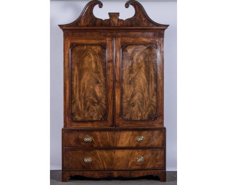 A George III mahogany linen press, swan neck pediment, central inlaid with a vase of flowers above a cavetto moulded cornice,