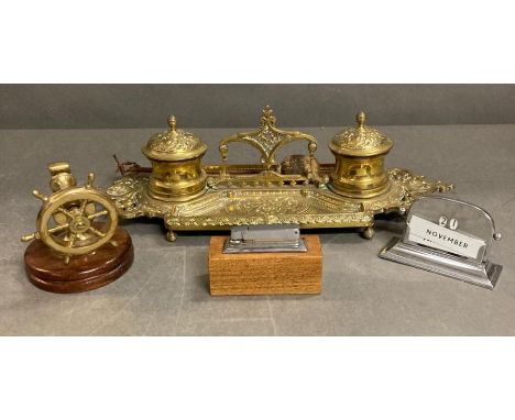 A selection of desk items to include a brass inkwell, ships wheel nut cracker lighter and calendar 