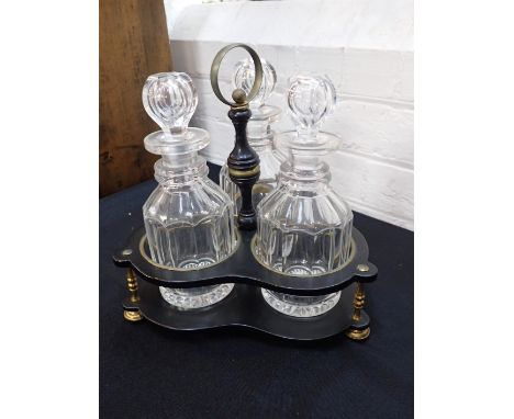 A 19TH CENTURY EBONISED WOOD AND BRASS MOUNTED THREE BOTTLE CRUETwith turned knopped and brass ring handle, shaped outline, 2