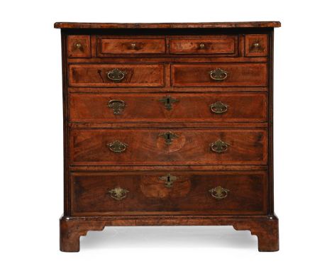 A GEORGE II WALNUT AND FEATHERBANDED CHEST OF DRAWERS CIRCA 1730 The upper central drawer with an inset leather writing surfa