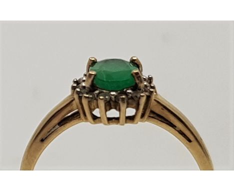 A 9ct. gold, emerald and clear stone ring, set central oval mixed cut emerald with border of clear round cut stones, together