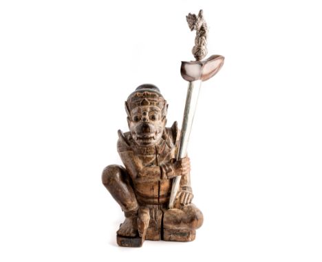 A JAVANESE KRIS IN CARVED WOOD STAND, 19TH CENTURY the silver repousse hilt in the form of a bird-headed deity, with wavy bla