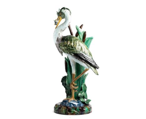 A JOSEPH HOLDCROFT MAJOLICA STICK STAND, CIRCA 1880 modelled as a heron with a fish in its beak standing on one leg beside a 