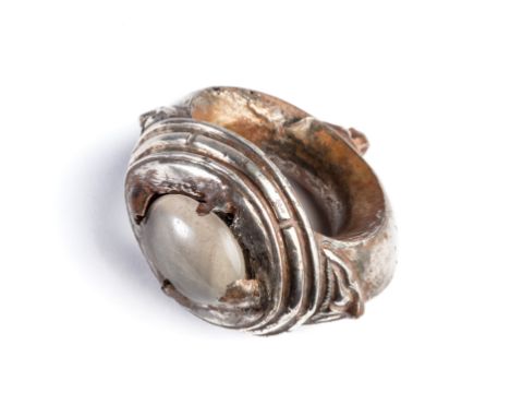 A KHMER OVER-SIZE SILVER RING, CAMBODIA, CIRCA 10TH CENTURY the bezel set with an oval rock crystal, the faceted shank with l