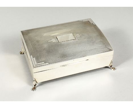 AN ENGINE TURNED SILVER TABLE CIGARETTE BOX with cedar wood liner on four claw and ball feet. 6.5ins long Birmingham 1936, ma