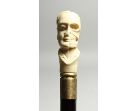 A BONE WALKING STICK 'HALF FACE, HALF SKULL' 35ins high