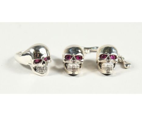 A PAIR OF SILVER SKULL CUFF LINKS AND RING, with ruby eyes.