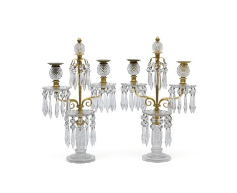 A pair of ormolu-mounted, cut and moulded glass two-light candelabraEarly 20th century Each with facet-cut finial flanked by 