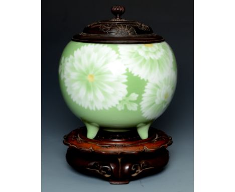 A Miyakawa Kozan Japanese globular bowl on tripod stud feet decorated with white and yellow chrysanthemums on an apple green 