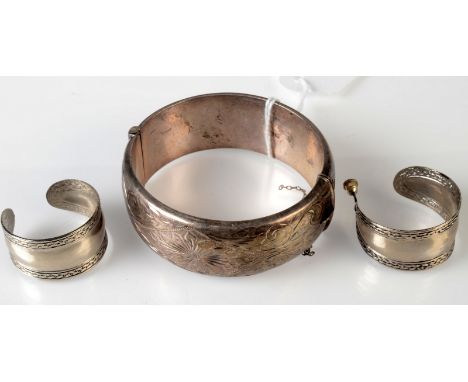 A hnged silver bangle, together with a pair of hoop earrings, one lacks fitting. 
