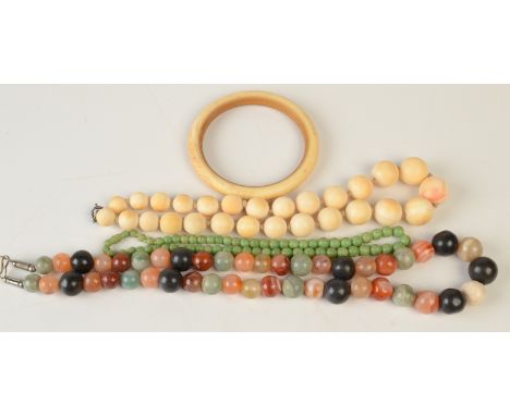 A hardstone bead necklace, two ivory necklaces and an ivory bangle.