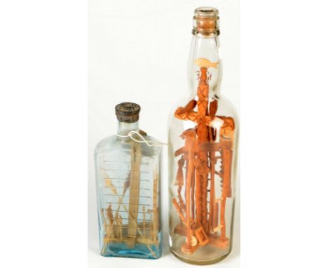 Two 'god in a bottle' folk art displays of carved wood Cornish miners tools, in glass bottles, heights 30cm and 19cm.