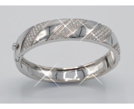 A French 18ct. white gold bangle with diagonal bands of pave set diamonds, weight 53.6g. (See illustration)