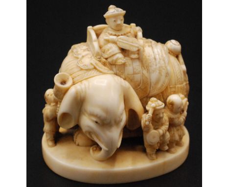 A Japanese ivory netsuke carved as an elephant standing four square and mounted with a throne style chair within which sits a