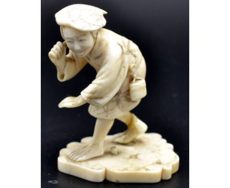 A Japanese ivory okimono, a peasant holding a knife neck high and bending, possibly seeking a prey, a tonkotsu and manju atta