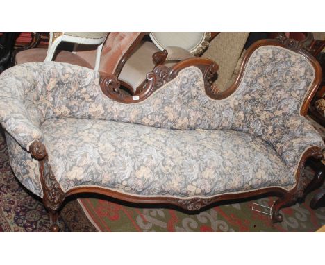 A Victorian buttoned walnut sofa, with shaped back and ornate carving on cabriole legs.