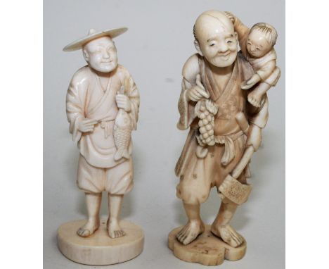 A Japanese ivory okimono, a standing father carrying his child over his right shoulder while holding an axe and a bunch of gr
