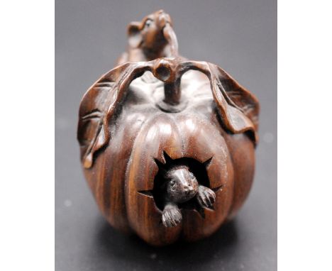 A Japanese wood netsuke, a pumpkin with stalk and foliage within which a rat has gnawed and looks outwards, signed in sosho. 
