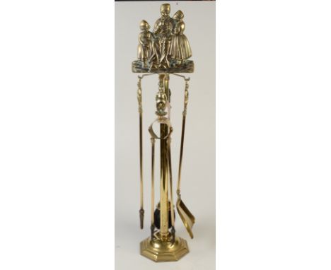 A large brass, four piece fireside companion set, the finial a seated Dutchman smoking a pipe and flanked by girls, with a st