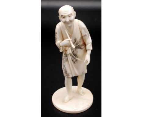 A Japanese sectional ivory okimono of a standing gentleman holding a pipe in his right hand while looking forward,his kiserzu