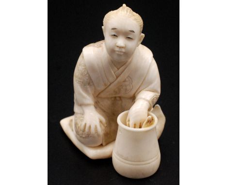 A Japanese ivory okimono, a youth squatting upon a cushion while popping his left hand intoa jar stood before him, his garmen