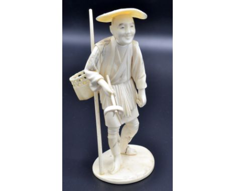 A Japanese ivory okimono of sectional workmanship carved as a standing farmer holding a trident bladed rake, on rounded base.